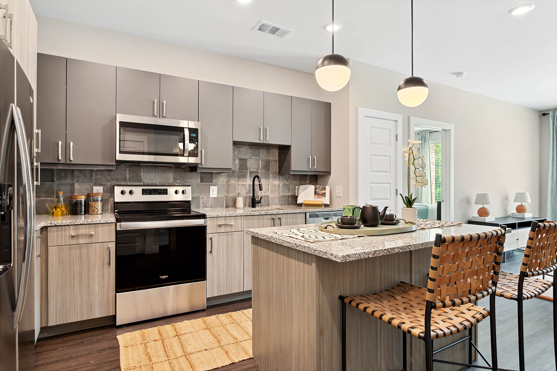 A modern, bright kitchen with an island overlooking the living room at the Verge Apartments in Atlanta, Georgia.